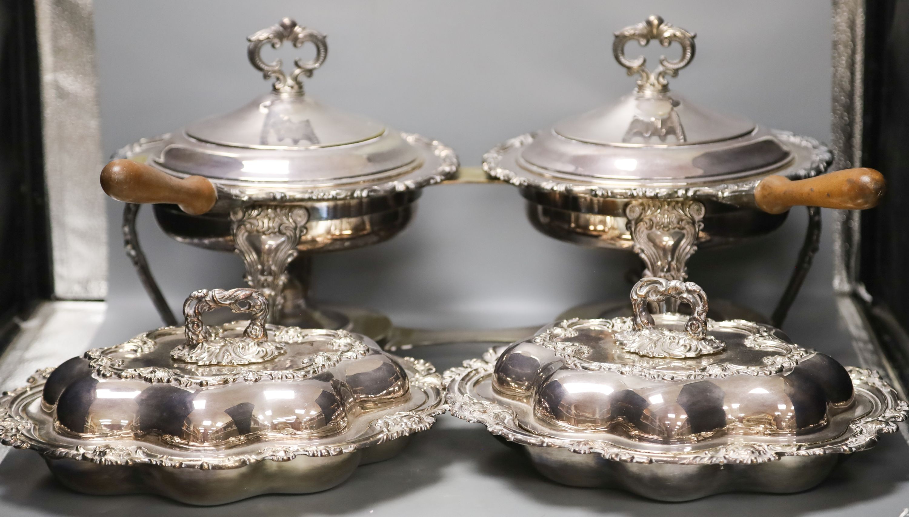 A pair of cast plated shaped oval entree dishes and covers and pair of linked cast plated breakfast braziers and covers, with turned wood handles